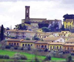 a group of houses with a clock tower in the background at La Libellula in Capannoli