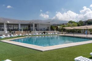 a large swimming pool with chairs and a building at Maison Jwar - Luxury A-Shape Cabins - A Unique Summer Getaway in Ḩārat at Taḩtā