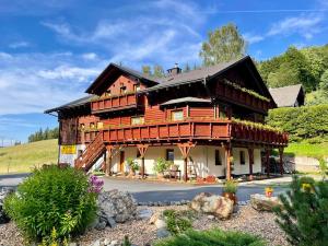 a large wooden house with a balcony at Pension Grizzly in Ludvíkov