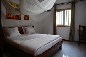 a bedroom with a bed with white sheets and a window at Executive Suites & Apartments - VIP Services in Kribi +62 photos