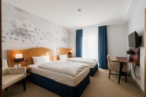 a hotel room with two beds and a tv at Hotel Das Lola in Essen