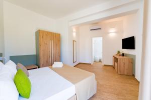 a bedroom with a white bed and a flat screen tv at Caladune Resort in Pizzo