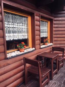 a porch with two benches and a table and windows at Pension Grizzly in Ludvíkov
