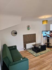 a living room with a green couch and a tv at The Chilux stylish apartment in Rainham