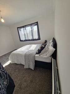 a white bedroom with a bed with a window at The Chilux stylish apartment in Rainham