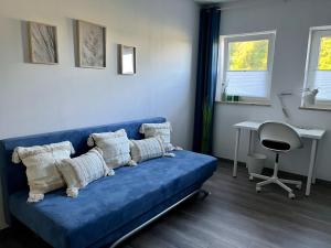 a blue couch with pillows in a room with a desk at Ferienwohnung Schöpf - Fränkische Schweiz in Obertrubach