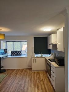 a kitchen with white cabinets and a large window at The Chilux stylish apartment in Rainham +26 photos