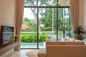 a living room with a couch and a large window at Neon Villa in Ko Phangan