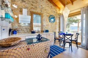 a kitchen with a table and chairs and a stone wall at Nous Village 2 in Alyki