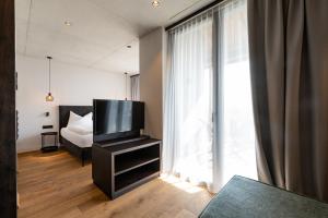 a bedroom with a tv and a bed and a window at View - AgriSuites in Caldaro +20 photos