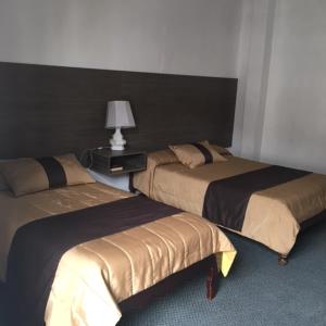 2 camas en una habitación con una lámpara en una mesa en Hostal Chordeleg, en Cuenca