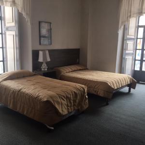 2 camas en un dormitorio con 2 ventanas en Hostal Chordeleg, en Cuenca