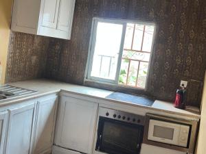 a kitchen with a stove and a microwave and a window at Sumanya guest house 6 in Sukuta +5 photos