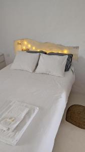 a white bed with white pillows and lights on it at Casas Velhinhas - Apartº Aconchego e Apartº Calmaria in Estremoz