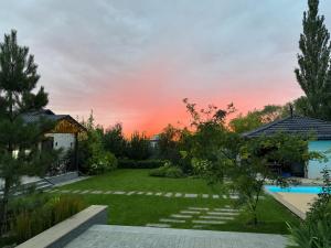 a garden with a sunset in the background at LouLou Hills in Uchastkovoyye Khozyaystvo SKhI