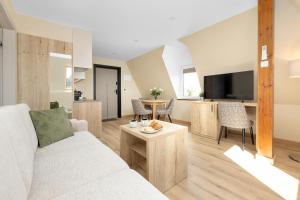 a living room with a white couch and a table at Dworek Zielińskich-Domki, Apartamenty, Podgrzewany basen, Parking in Rewal