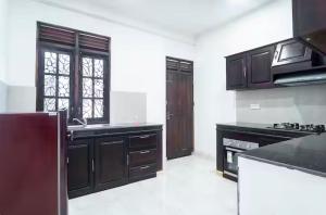 a kitchen with black cabinets and black counter tops at The Ivy Grove in Mahabage +2 photos