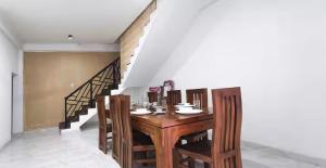 a dining room with a wooden table and a staircase at The Ivy Grove in Mahabage