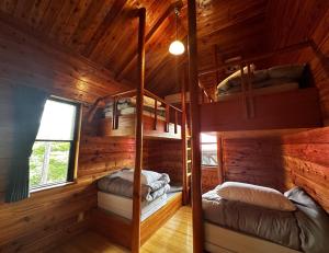 two bunk beds in a cabin with wooden walls at Maruta なんもく村 in Minamimaki