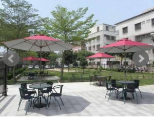 a group of tables and chairs with umbrellas in a park at Fengming B&B in Jinning