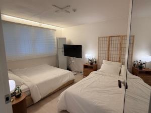 a bedroom with two beds and a flat screen tv at 헤이데이서울 in Seoul