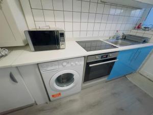 a kitchen with a microwave and a washing machine at Romford 4-Bed Home Sleeps 7 with Garden & Parking in Romford