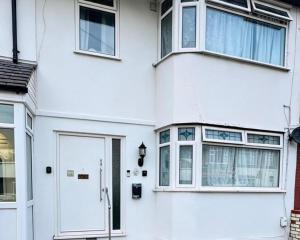 a white house with a white door and windows at Romford 4-Bed Home Sleeps 7 with Garden & Parking in Romford