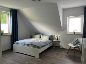 a bedroom with a bed and two windows and a chair at Ferienwohnung Schöpf - Fränkische Schweiz in Obertrubach +19 photos