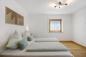 a white bedroom with two beds and a window at Ferienwohnung am Alenberg in Münsingen
