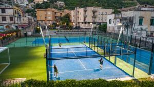 a group of people playing tennis on a tennis court at Hotel San Pietro in Maiori