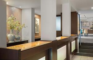 a lobby with two vases on a counter with pillars at Leonardo Hotel München City Center in Munich