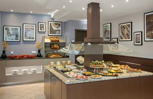 a kitchen with a buffet of food on a counter at Leonardo Hotel München City Center in Munich