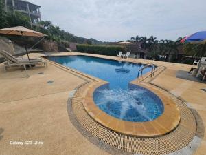a swimming pool in a yard with an umbrella at Chaya village F shared pool jacuzzi in Phra Ae beach