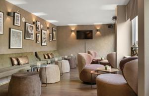 a waiting room with couches and tables and chairs at Leonardo Hotel München City Center in Munich