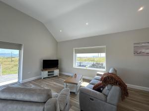 a living room with two couches and a tv at Ballyconneely Lodge in Ballyconneely +6 photos