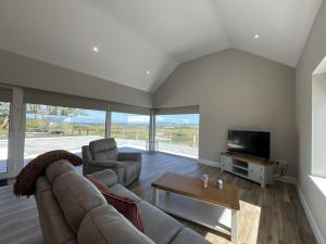 a living room with a couch and a tv at Ballyconneely Lodge in Ballyconneely