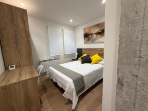 a bedroom with a bed with yellow pillows on it at MTM Rooms in Santander