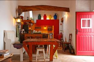 a kitchen with a wooden table and a red door at Casa Palheiro, Aldeia da Pedralva in Vila do Bispo