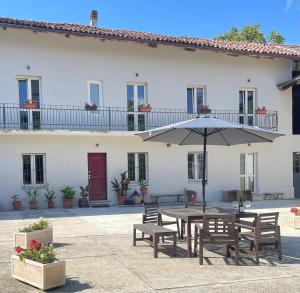 a table with an umbrella in front of a building at Tenuta Nissole in Rocchetta Tanaro