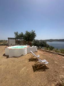 a couple of lounge chairs and a swimming pool at Herdade Monte da Tapada in Alqueva +31 photos