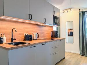 a kitchen with white cabinets and a sink at HabeDere Apartments Allgäu in Obergünzburg