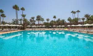 a large swimming pool with chairs and palm trees at SOL by Meliá Oasis Marrakech - All Inclusive in Marrakesh