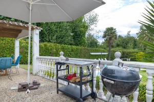 a patio with a grill and a table and an umbrella at Acogedor chalet rústico in Cambre