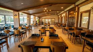 a restaurant with wooden tables and chairs and windows at Yoncalı Termal Spa Otel in Ortaca
