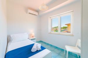 a white bedroom with a bed and a window at CalaDune Villas in Pizzo