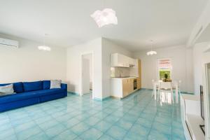 a living room with a blue couch and a kitchen at CalaDune Villas in Pizzo