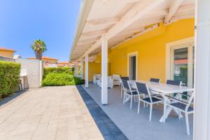 a patio with a table and chairs and a yellow house at CalaDune Villas in Pizzo