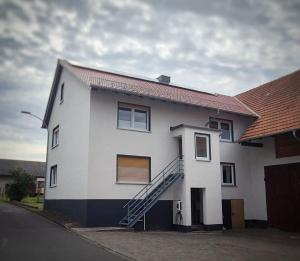 a white house with a staircase on the side of it at Der Teichhof in Grandenborn +13 photos