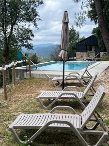 two lawn chairs and an umbrella next to a swimming pool at Refúgio do Saltadouro - Entre o Gerês e a Cabreira in Ruivãis