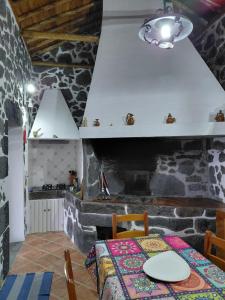 a kitchen with a table and a stone wall at Casa do Bernardo in Feiteira